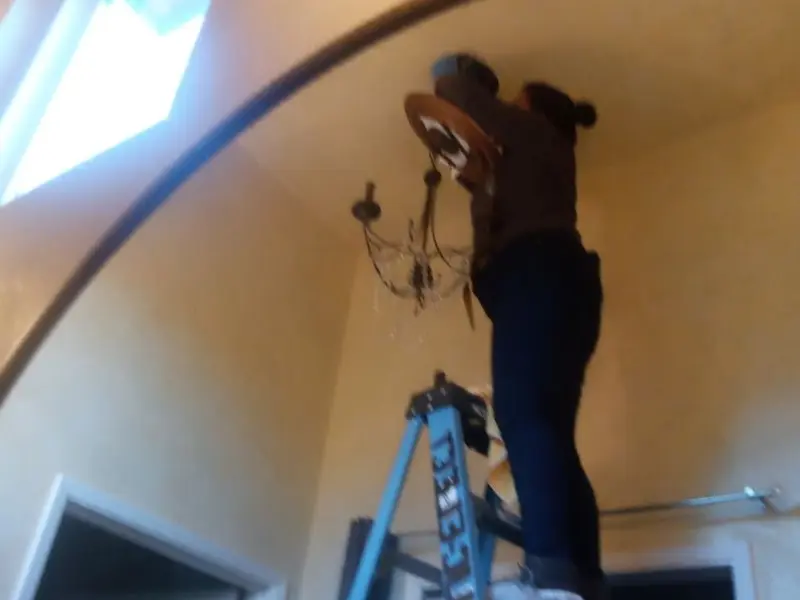 Electrician installing a chandelier in a Lake Stickney residence